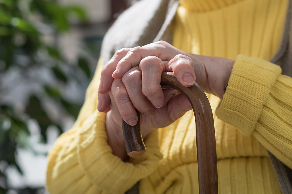 Vieille femme assise avec ses mains sur une canne