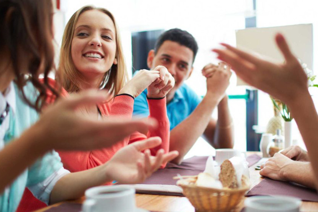 Des personnes proches aidantes discutent autour d'une table sur laquelle il y a du café et une corbeille de pain lors d'une des soirées-causeries bienveillantes