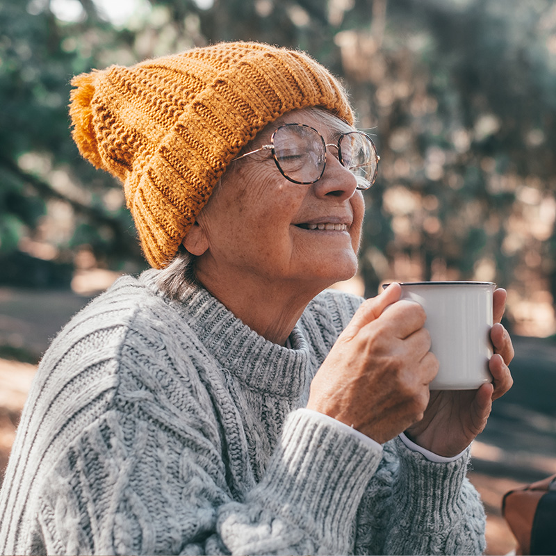 Femme âgée assise sur un banc de parc à l'automne, profite de son plan d'action personnalisé.