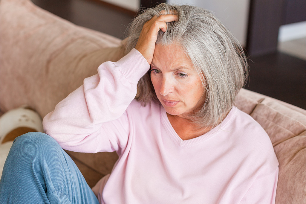 Femme assise sur un divan qui est découragée et fatiguée