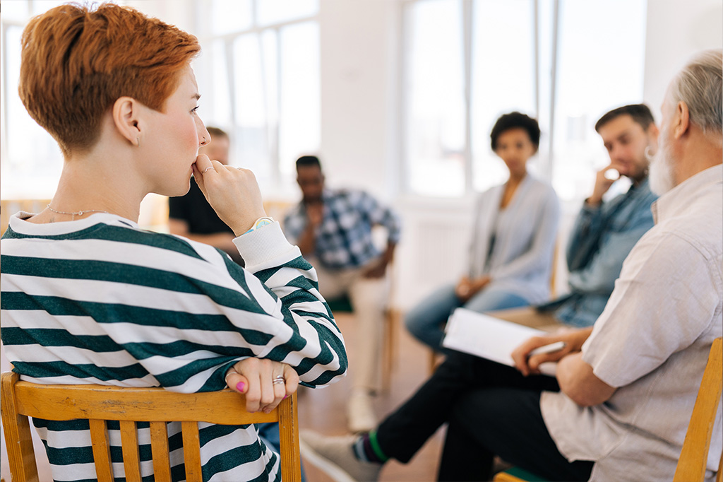 Femme dans un groupe d'entraide qui écoute attentivement un autre membre.