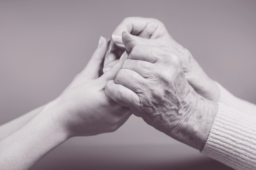 Une femme âgée serre les mains d'une autre femme plus jeune.